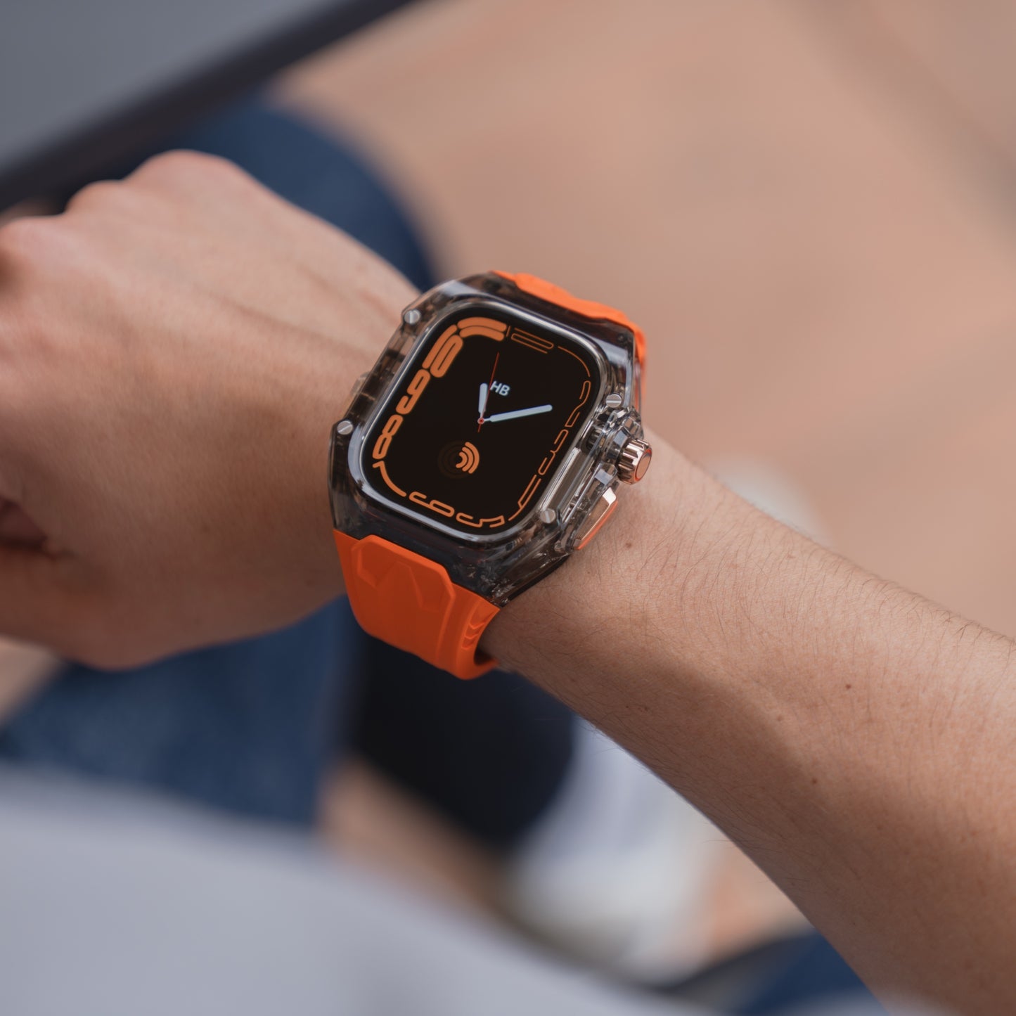 Eine Person trägt ein arktisband Apple Watch Armband "Armor Fusion" mit Silikonband, Hardcase und einer schwarz-orangen Digitalanzeige am Handgelenk.