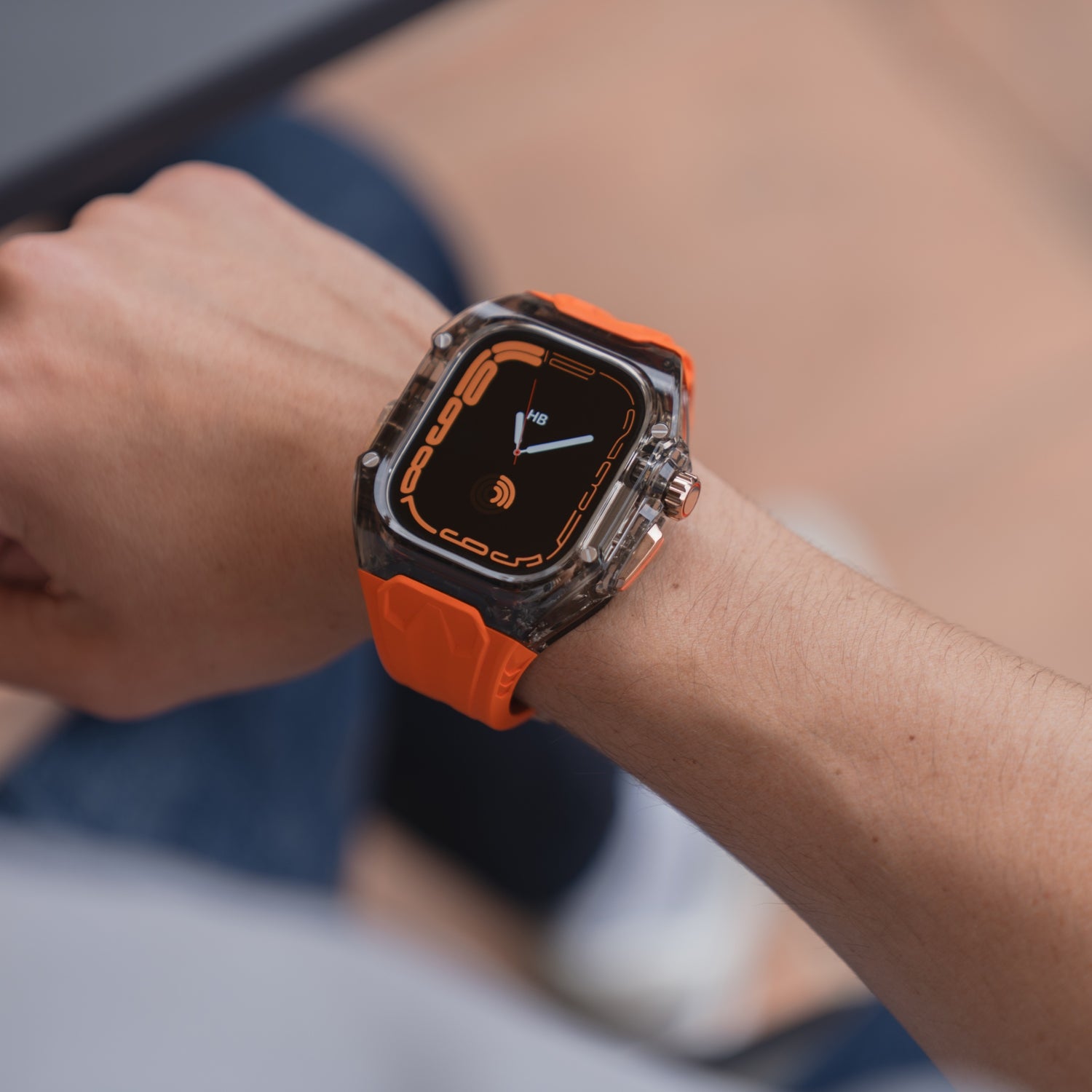 Eine Person trägt ein arktisband Apple Watch Armband "Armor Fusion" mit Silikonband, Hardcase und einer schwarz-orangen Digitalanzeige am Handgelenk.