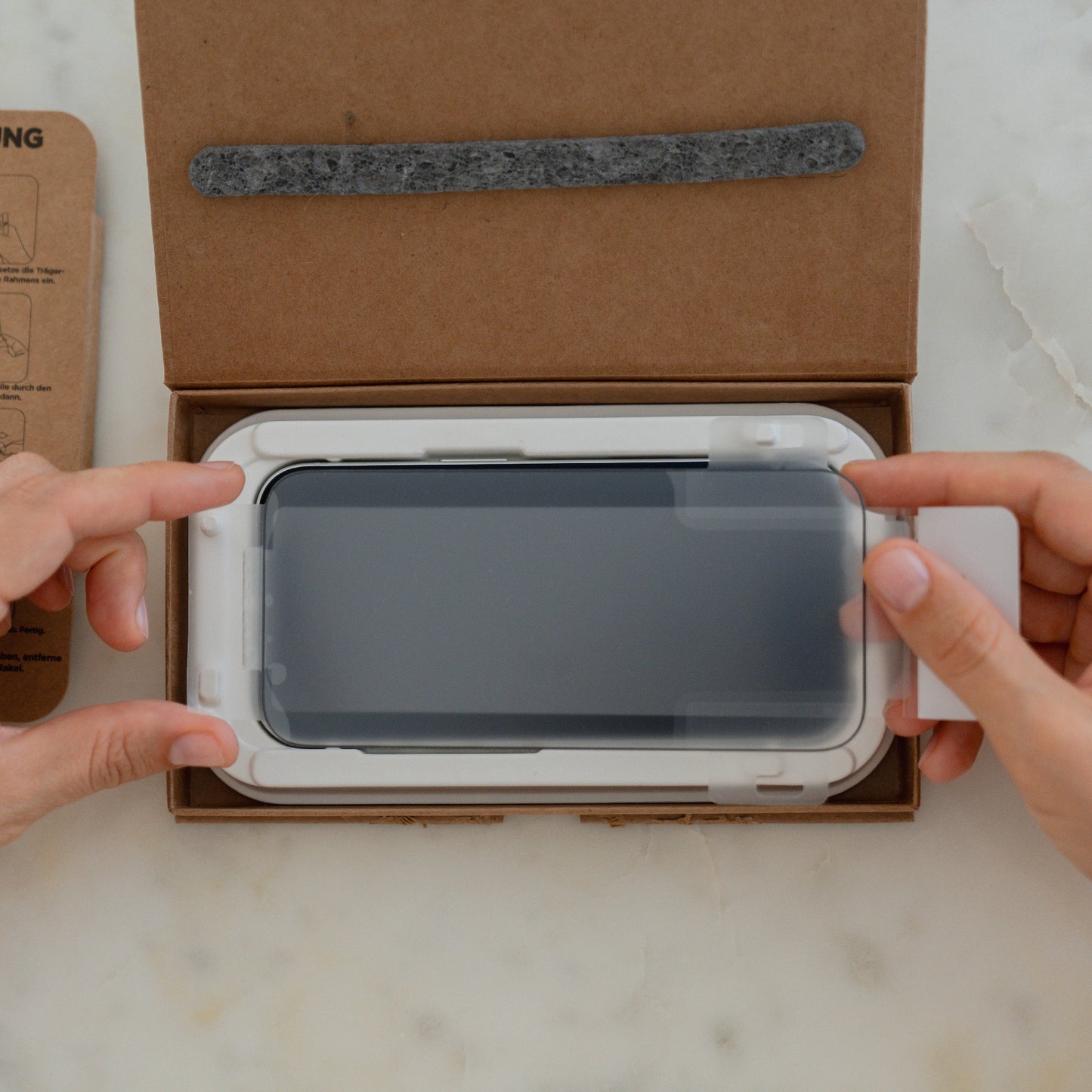 Das arktis 2er Set iPhone 17 Pro Max REVOLUTION Glas-Displayschutz wird mit Hilfe des EZ.INSTALL Box Kits angebracht, wobei die hochwertigen arktis Glas-Displayschutzfolien sauber in einem Markenkarton verpackt sind.