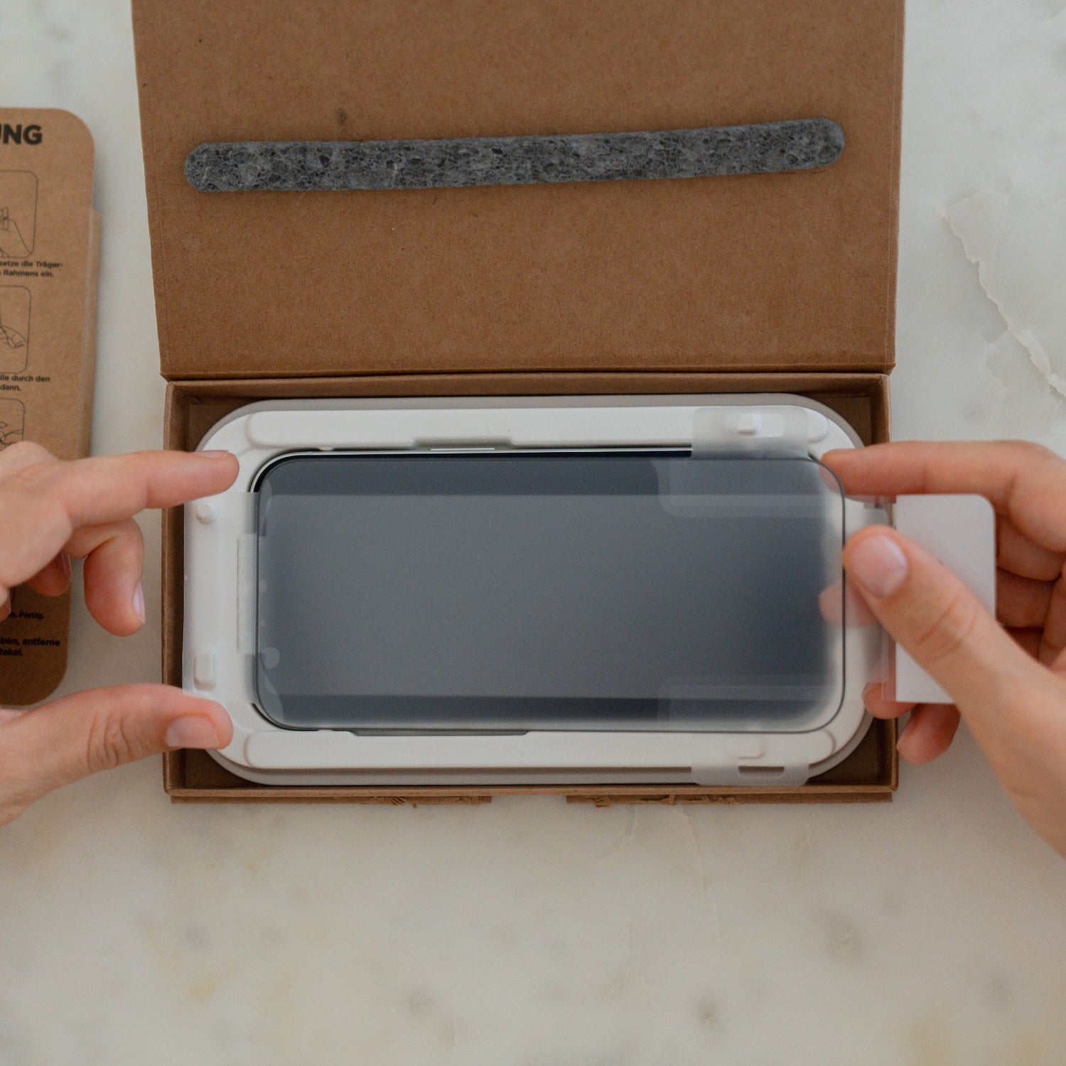 Das arktis 2er Set iPhone 17 Pro Max REVOLUTION Glas-Displayschutz wird mit Hilfe des EZ.INSTALL Box Kits angebracht, wobei die hochwertigen arktis Glas-Displayschutzfolien sauber in einem Markenkarton verpackt sind.