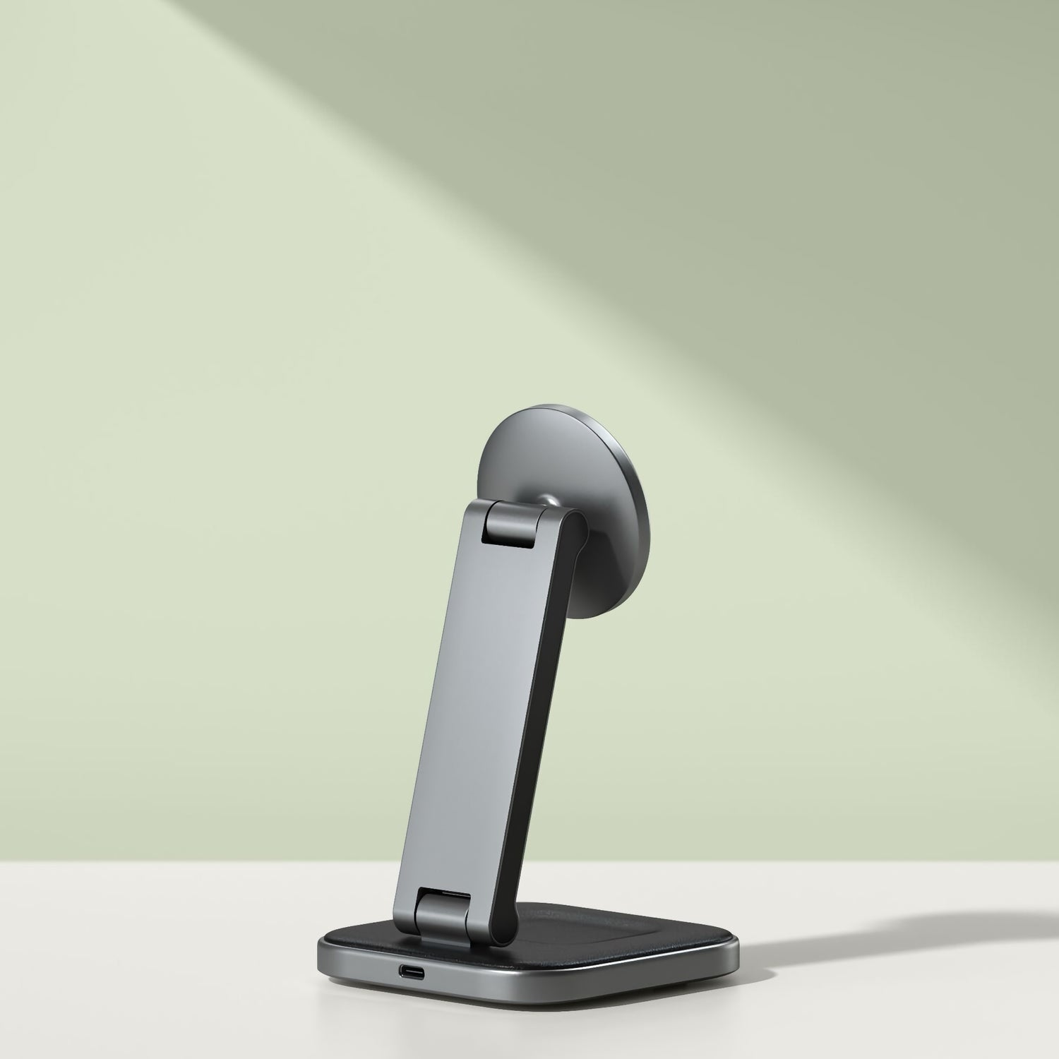 Der Satechi 2-in-1 Foldable Qi2 Wireless Charging Stand von Satechi ruht auf einer weißen Oberfläche mit einem hellgrünen Hintergrund und bietet einen eleganten, modernen Stil für das Aufladen Ihres Telefons.