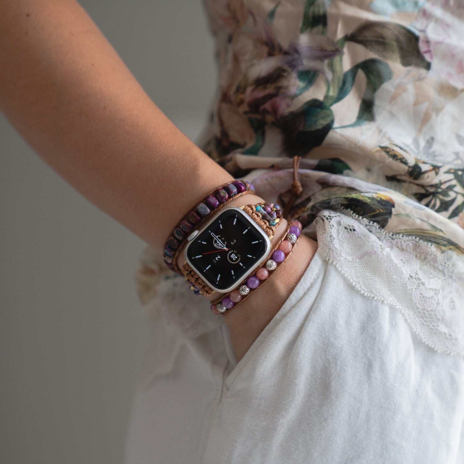 Jemand trägt ein arktisband Apple Watch Armband "Dream Catcher" von arktisband, mit einem Edelstahladapter und Boho-Perlenarmbändern, und steckt die Hand in die Tasche einer weißen Hose.