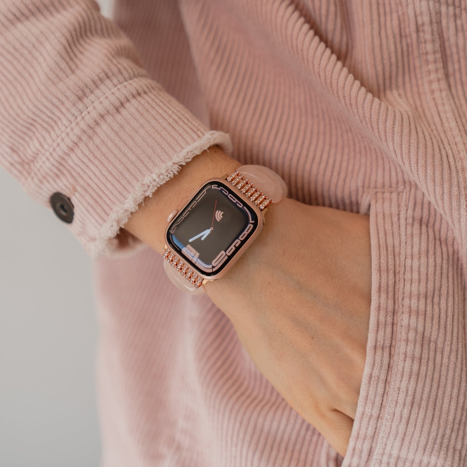 Eine Person, die die arktisband Apple Watch "Stone Pearl" von arktisband trägt, mit einer rosa Cordjacke und einer Hand in der Tasche.