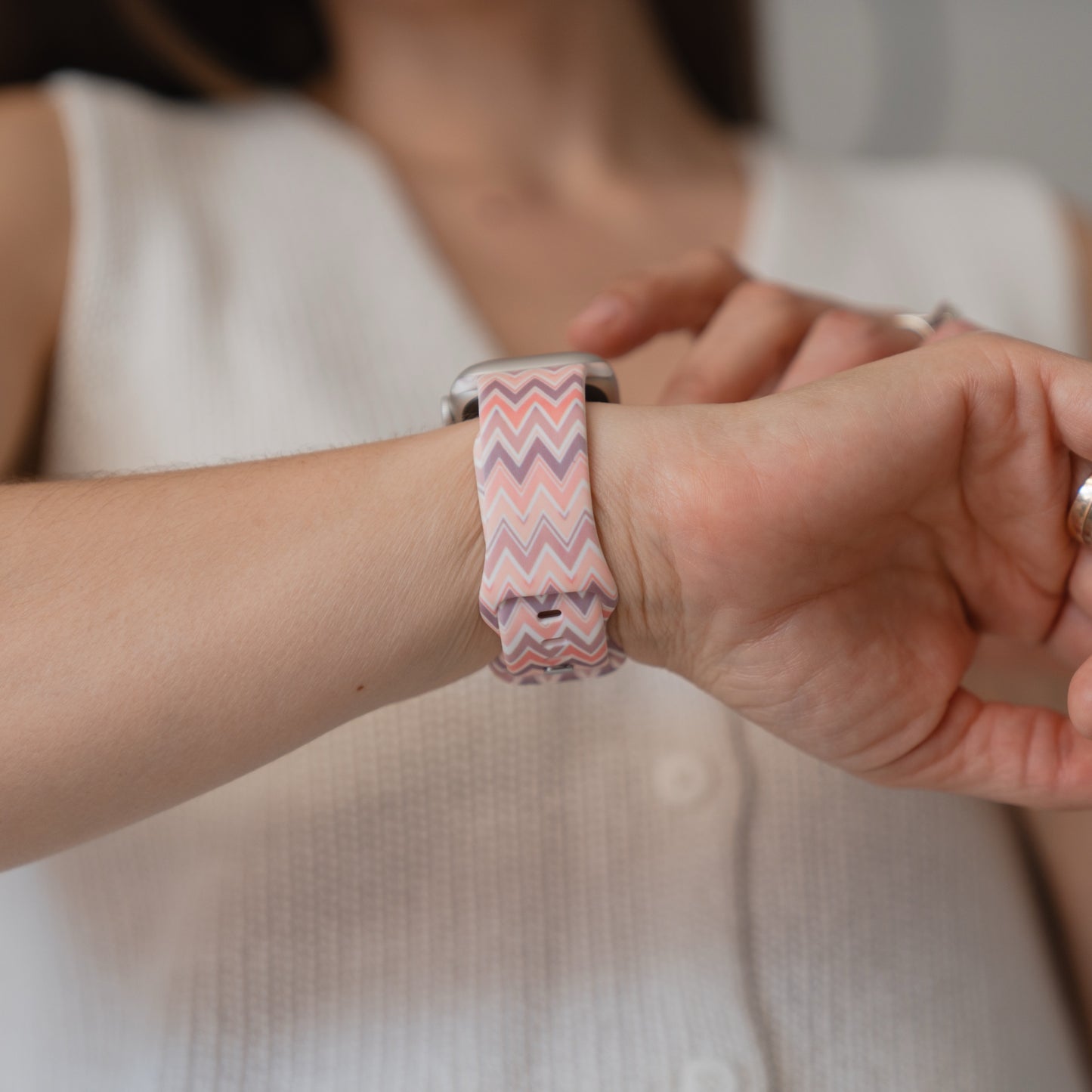 Eine Person, die das arktisband Vintage Boho Apple Watch Armband von arktisband mit einem rosa Zickzack-Muster und einem ärmellosen weißen Top trägt, bereit für sportliche Aktivitäten.