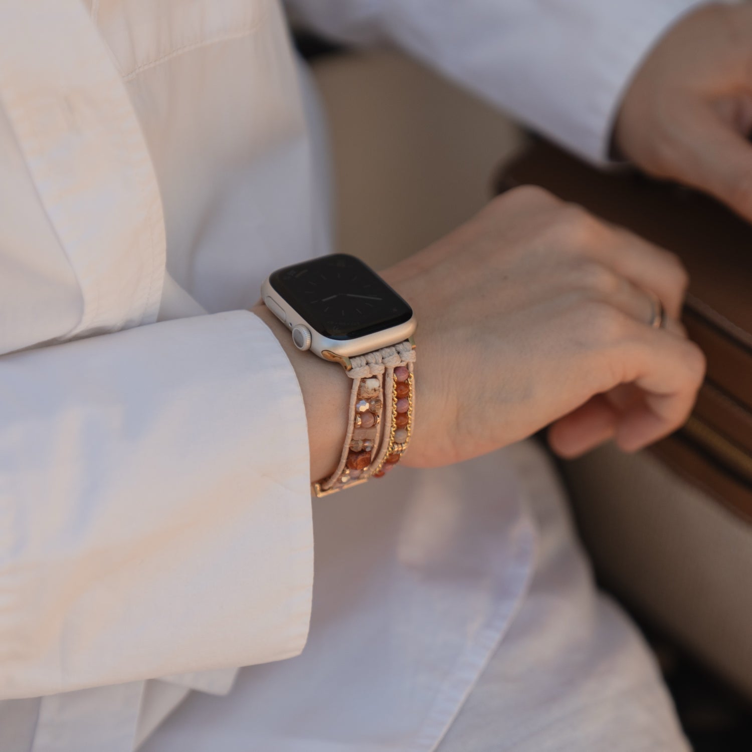 Nahaufnahme einer Person, die das Apple Watch-Armband „Sunset Spirit“ von arktisband trägt, kombiniert mit einem weißen Langarmhemd für einen modernen, schicken Look.