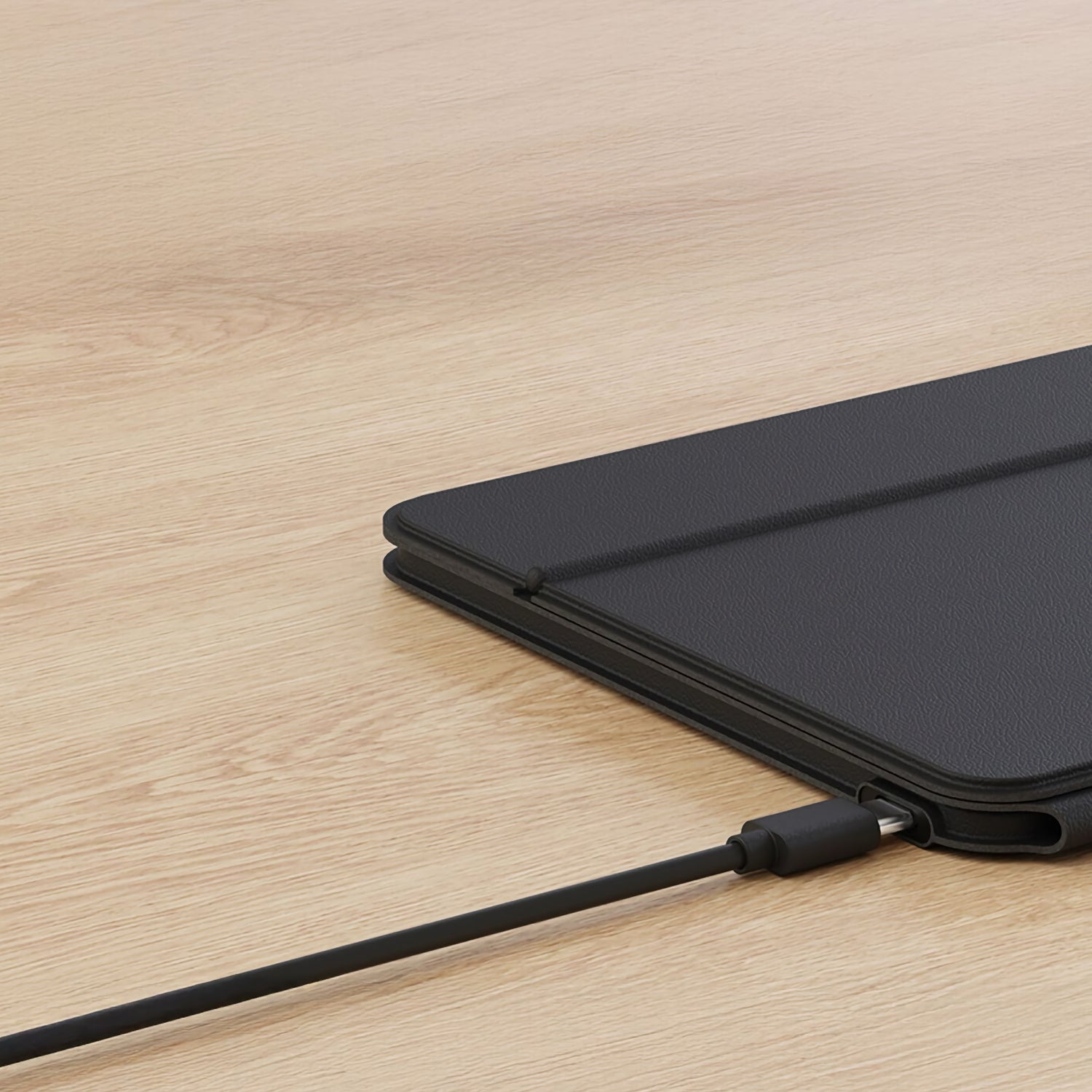 Ein schwarzes Tablet in einem Etui sitzt auf einer hellen Holzoberfläche mit einem schwarzen Kabel und zeigt, warum das Satechi OntheGo Bluetooth Keyboard mit Ständer von Satechi perfekt für bequemes Tippen und Portabilität ist, wo immer Sie arbeiten.