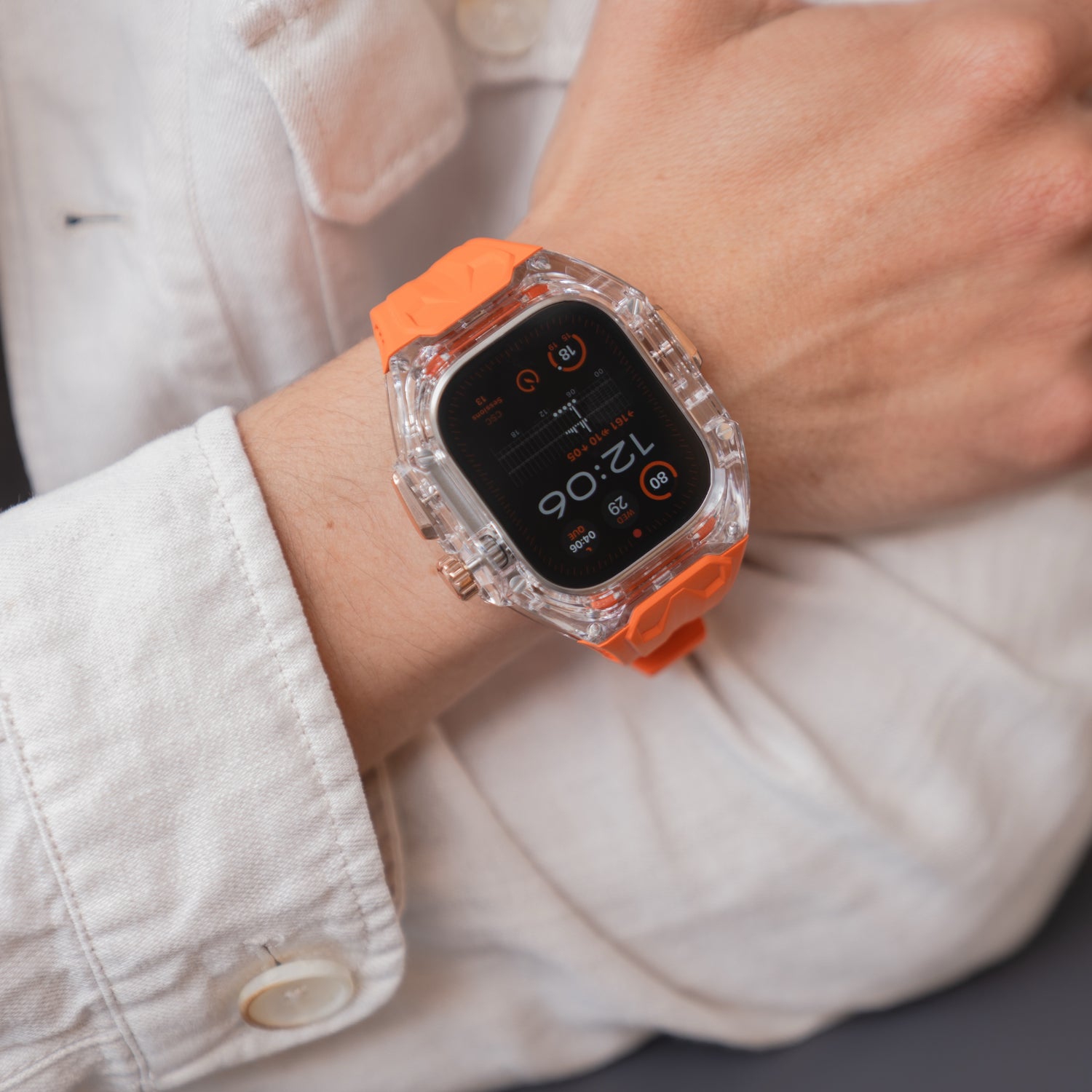 Eine Person, die das arktisband Apple Watch Armband "Armor Fusion" mit transparentem Hardcase und orangefarbenem Silikonband trägt, bekleidet mit einer weißen Jacke.