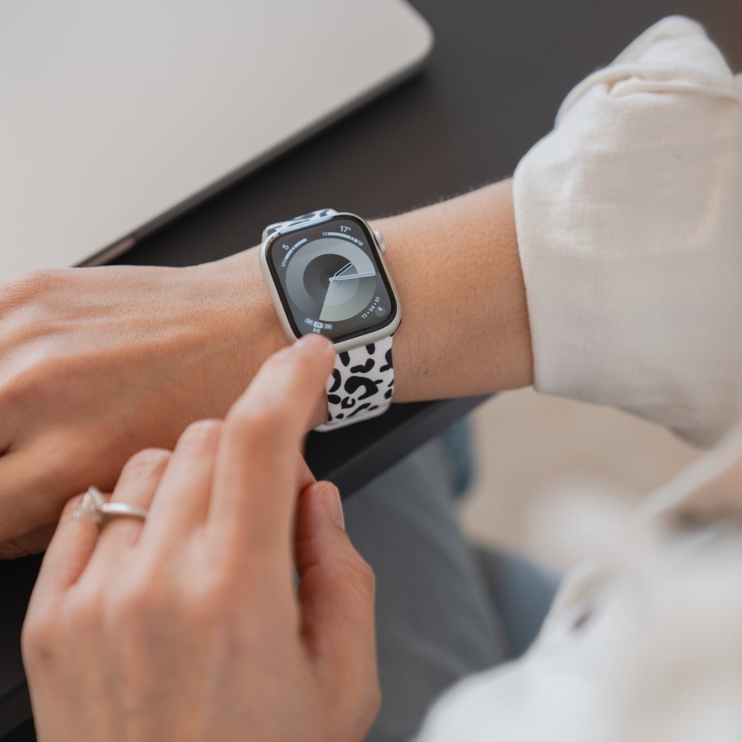 Mit einem arktisband Snow Leopard Apple Watch Armband von arktisband tippt eine Person auf ihre Apple Watch, während sie am Laptop arbeitet.