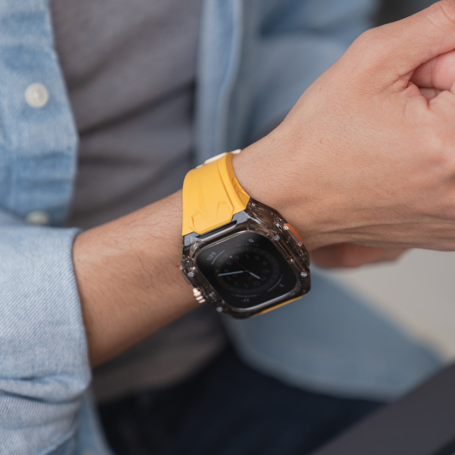 Eine Person trägt ein arktisband Apple Watch Armband "Armor Fusion" mit einem gelben Silikonband und einer Hartschalenhülle und passt es an ihr Handgelenk an.